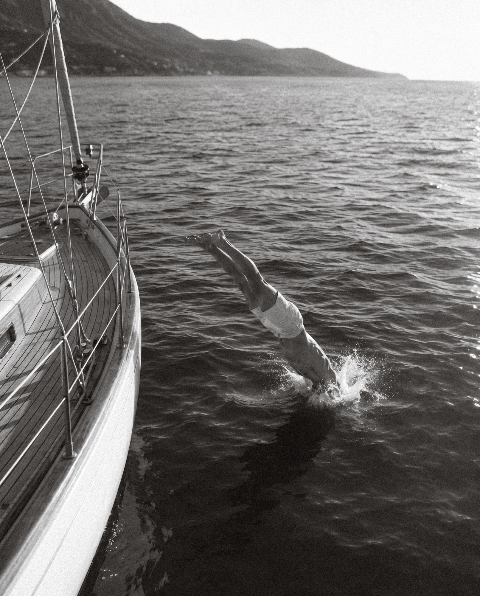 Swimmer diving from a sailing boat, black and white