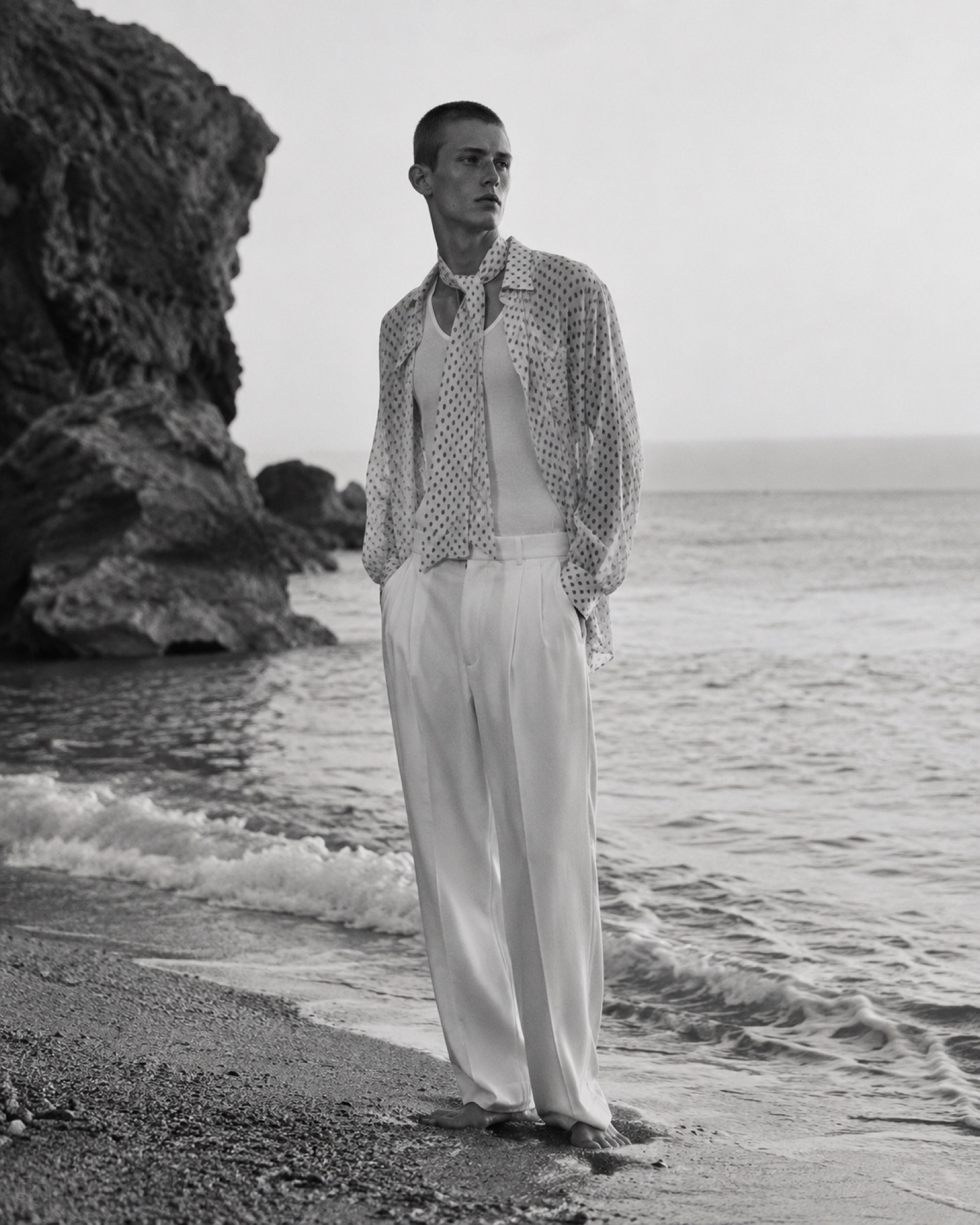 Man in a striped shirt on a rocky shore, black and white